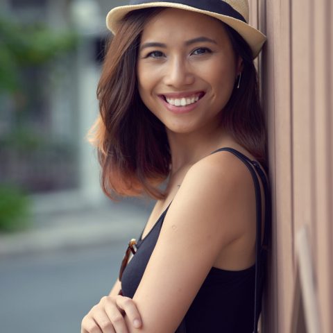 Portrait of smiling Vietnamese young woman standing at the wall